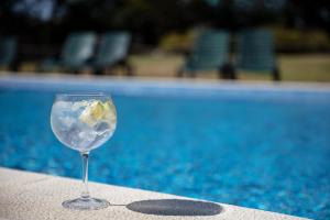 a wine glass sitting on a table next to a swimming pool at Campanile Lisboa Sud - Setubal in Setúbal