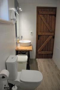 a bathroom with a toilet and a sink and a wooden door at LIORIZA Country Houses in Kalamaki