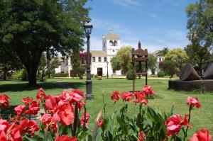 a park with red flowers in front of a building at Hotel Cortijo El Esparragal in Gerena