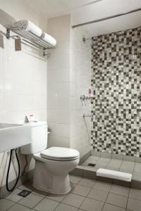 a white bathroom with a toilet and a shower at Amaris Hotel Pancoran in Jakarta