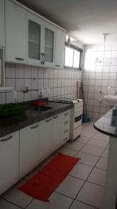 Apartamento em Fortaleza في فورتاليزا: مطبخ مع دواليب بيضاء وسجادة حمراء