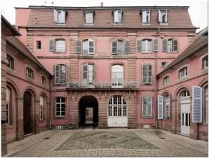 un gran edificio de ladrillo rosa con puerta blanca en Appartement Le 22 - Colmar Centre Parking Privatif en option, en Colmar