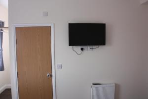 uma televisão de ecrã plano pendurada numa parede em Daisy Hotel em Londres