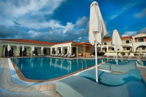 a pool at a hotel with an umbrella at Messina Resort Hotel in Kyparissia