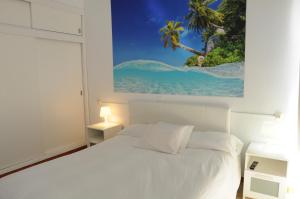 um quarto com uma cama branca e uma pintura na parede em Mini Golf Apartments em Canyamel