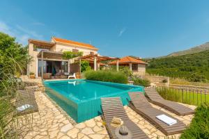 a swimming pool with chairs and a house at Villa Turcoisinus HH in Mokošica