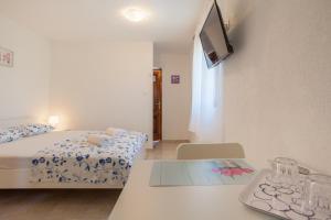 a room with a bed and a table and a tv at Apartments Dandić in Orlec