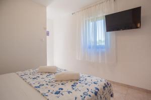 a room with a bed with two pillows and a television at Apartments Dandić in Orlec