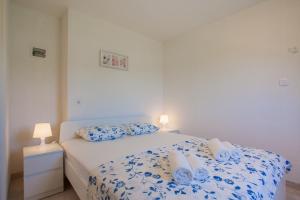 a bedroom with a bed with blue and white sheets and pillows at Apartments Dandić in Orlec