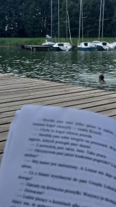 książka siedząca na przystani z łodziami w wodzie w obiekcie Dom nad Wigrami w mieście Suwałki