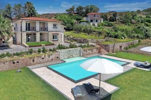 a house with a swimming pool and an umbrella at Villa Turquoise in Magomadas