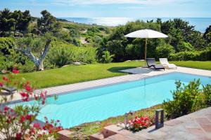 a swimming pool with an umbrella and a chair at Villa Turquoise in Magomadas