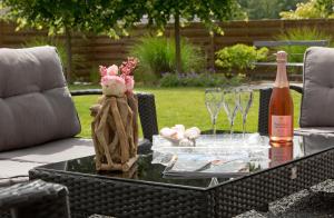 - une table de patio avec une bouteille de vin et des verres dans l'établissement Aux Chambres d'à Coté, à Courcelles-Sapicourt