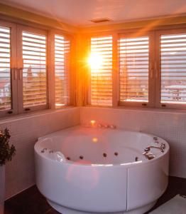 - une grande baignoire blanche dans une chambre avec fenêtres dans l'établissement Hotel Veter, à Ruše