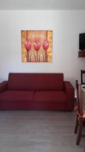 un divano rosso in un soggiorno con un dipinto sul muro di Il Mandorleto a Cirò Marina