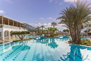 a swimming pool at a resort with palm trees at Lindos Imperial Resort & Spa in Kiotari
