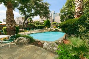 uma piscina num jardim com cadeiras e árvores em The Crockett Hotel em San Antonio