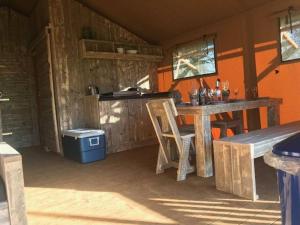 an outdoor kitchen with a table and a bench at Lapwing Safari Tent in Cheltenham