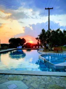 une grande piscine avec un coucher de soleil en arrière-plan dans l'établissement Asteris Village, à Gerakini