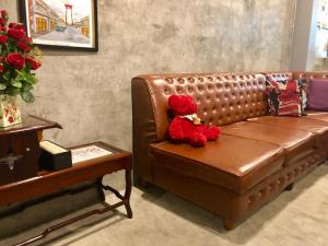 a red teddy bear sitting on a brown leather couch at Alley living rama8 in Bangkok