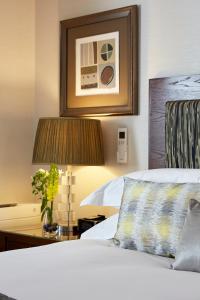 ein Hotelzimmer mit einem Bett und einem Tisch mit einer Lampe in der Unterkunft Cheval Knightsbridge in London