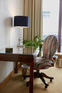 a room with a desk with a chair and a lamp at Cheval Knightsbridge in London