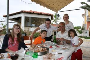 un grupo de personas sentadas en una mesa con comida en Metaxa Hotel, en Kalamaki