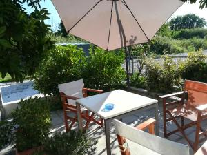 a table and chairs with an umbrella on a patio at The Garden in Pefki