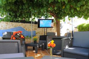 d'une terrasse avec des chaises et une télévision sous un arbre. dans l'établissement Mini Golf Apartments, à Canyamel