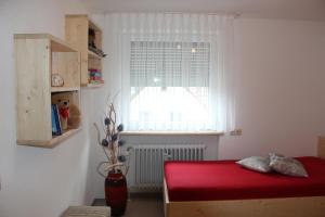 ein Schlafzimmer mit einem roten Bett und einem Fenster in der Unterkunft Ferienwohnung Haus am Dürrberg "St. Barbara" in Warmensteinach