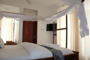 Villa Dahl Beach Resort في دار السلام: غرفة نوم بسرير مع مظلة ونوافذ