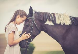 Ein junges Mädchen steht neben einem Pferd in der Unterkunft Golchener Hof in Golchen