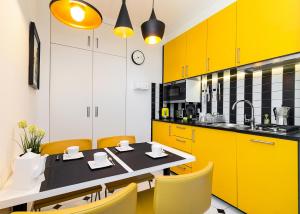 kuchnia z żółtymi szafkami oraz stołem i krzesłami w obiekcie At the Fountain Apartment w Warszawie