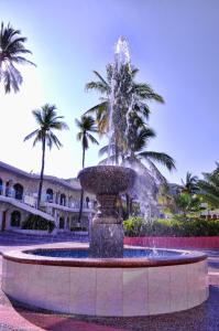 a fountain in front of a building with palm trees at Hotel Costa Azul in Acapulco