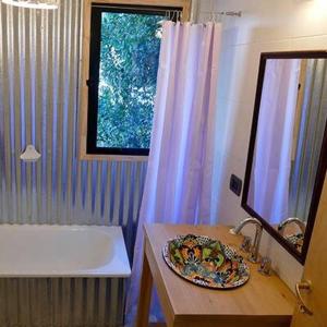 un baño con lavabo y una mesa con una placa. en Casas Chaura en El Bolsón