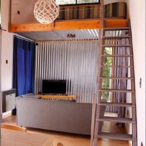 Sala de estar con cama elevada y escalera en Casas Chaura en El Bolsón
