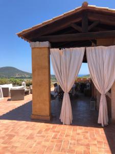 a pavilion with white curtains and a table and chairs at Chia Villa Violet in Chia