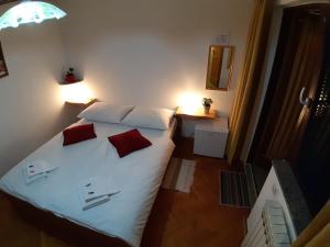 1 dormitorio con 1 cama con sábanas blancas y almohadas rojas en House Osana, en Grabovac