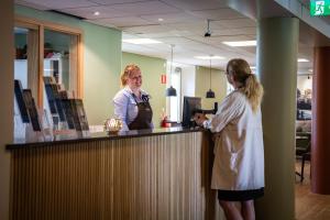 two women standing at a counter in an office at Hotel Hehrne Kök & Konferens in Vänersborg