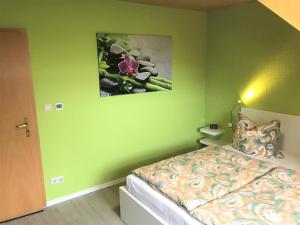 a green bedroom with a bed and a picture on the wall at Ferienwohnung Heymann in Hörnitz