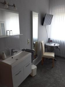 een badkamer met een wastafel, een stoel en een spiegel bij Pension Heib in Cochem