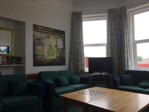 a living room with couches and a table and a tv at YHA Isle of Wight Totland - Partner in Totland