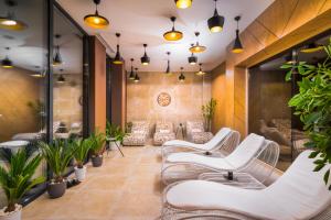 uma sala de espera com cadeiras brancas e plantas em Hotel Sevtopolis Medical & SPA em Pavel Banya