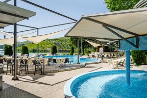 a patio with tables and chairs and a swimming pool at Romantique Veles Hotel in Veles