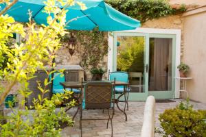 un patio con mesa, sillas y sombrilla en Casa La Premsa at Masia Nur Sitges, Adults only, en Canyelles