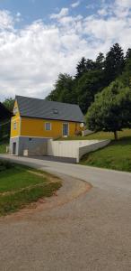 a yellow house on the side of a road at Ferienwohnung Tauschmann in Sankt Margarethen an der Raab