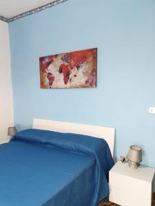 a blue bedroom with a bed and a painting on the wall at Domus Hera in Capaccio-Paestum