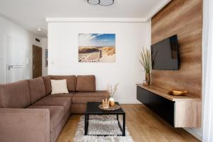 ein Wohnzimmer mit einem Sofa und einem TV in der Unterkunft Apartament przy Plaży / Klifowa in Rewal