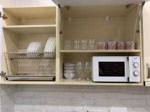 a kitchen with a microwave and plates and glasses at Loft Batumi in Batumi