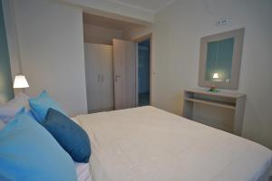 a bedroom with a bed with blue pillows and a window at Evel House in Skala Kallirachis